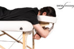 Personne couchée sur une table de massage avec la tête dans un kit têtière